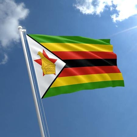 The flag of Zimbabwe flying against a blue sky.