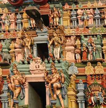 Detail of a south Indian temple tower covered in brightly painted statues of gods and figures.